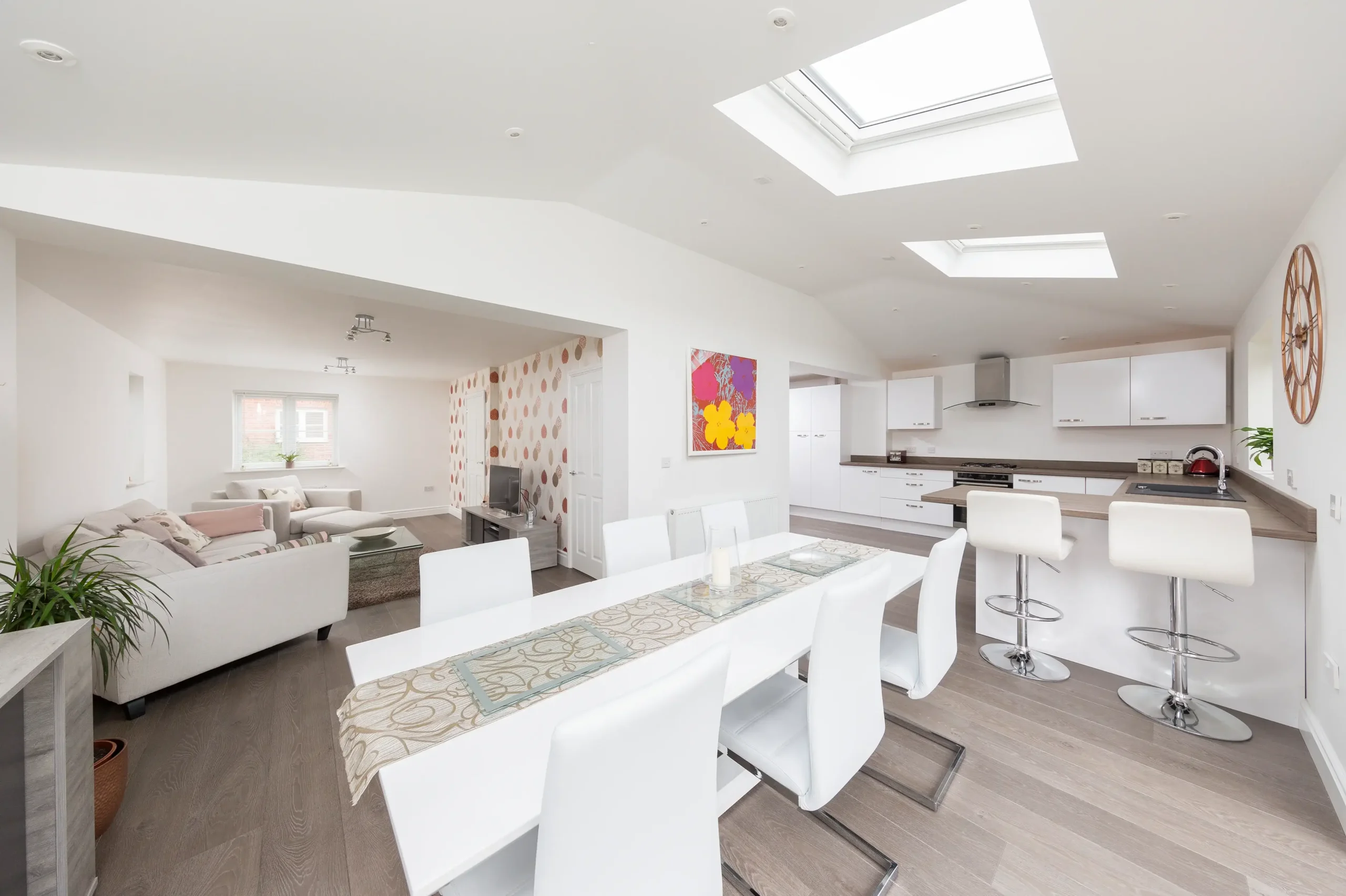 Open-plan kitchen, dining, and living area with modern white interiors.