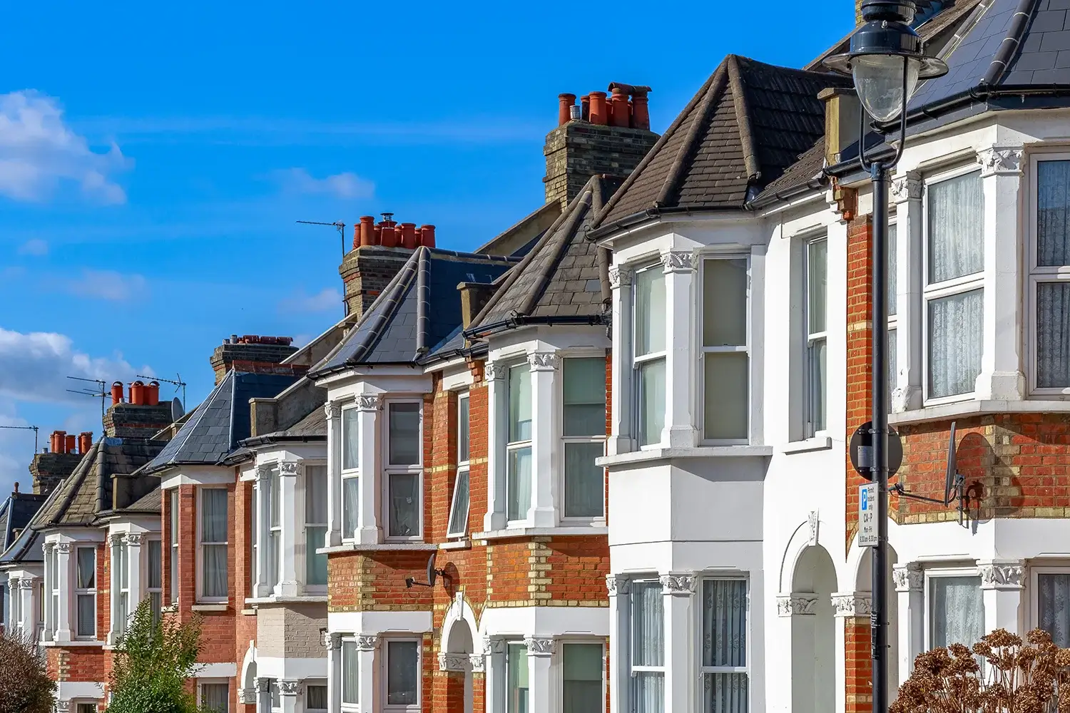 Row of traditional Victorian terrace houses with bay windows on a sunny London street